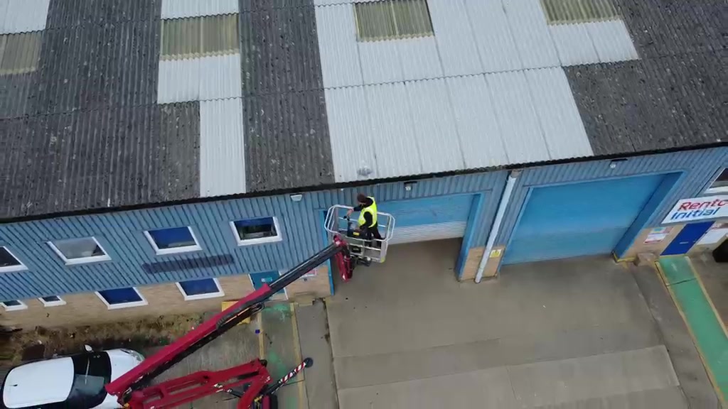 Commercial roof part-cleaned from the platform: dirty grey panels beside freshly cleaned white panels